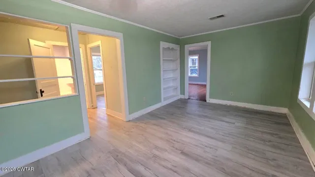 a view of an empty room with wooden floor and a window