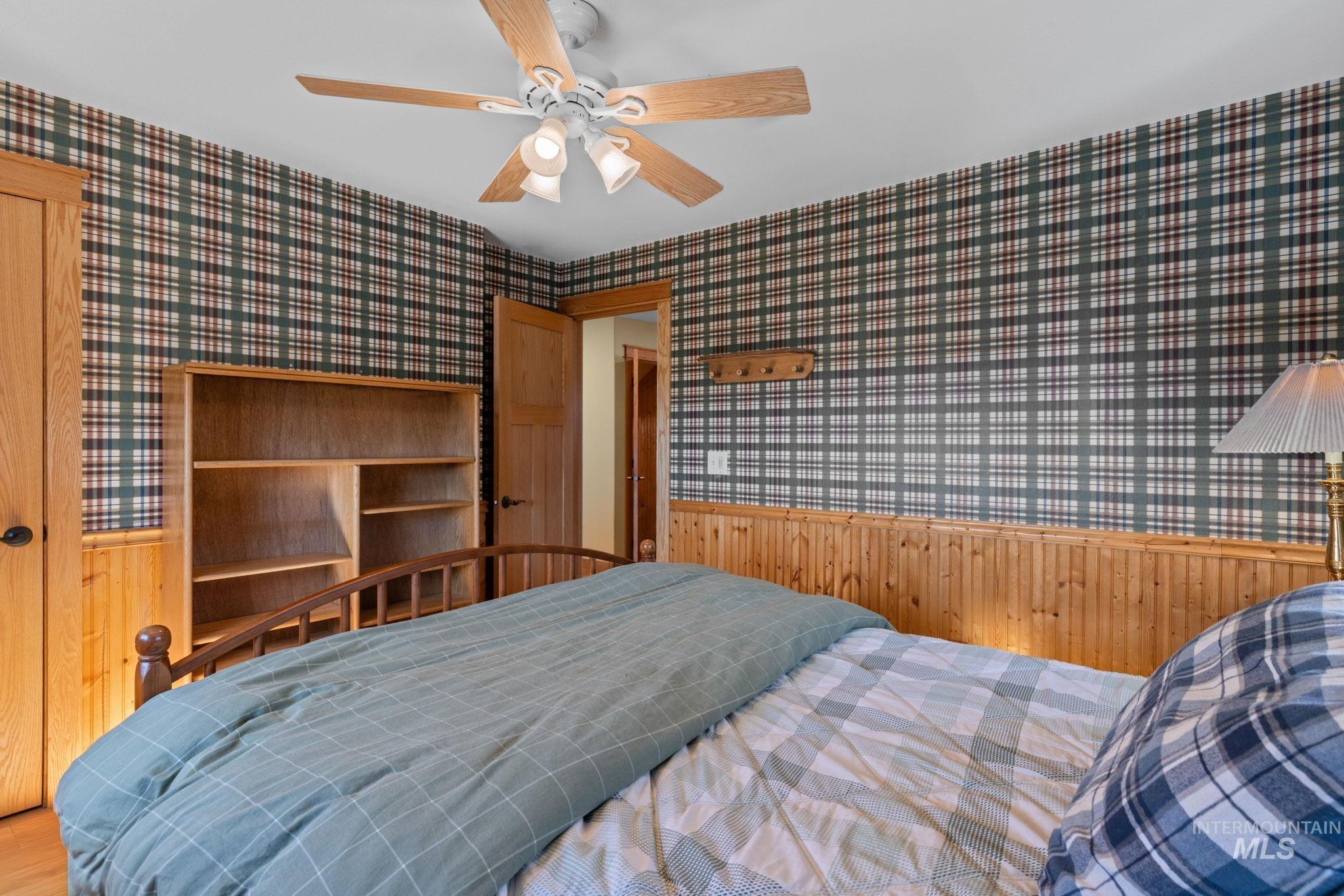1199 Walker Road Viola, ID 83872 - Photo 21 of 50 Bedroom featuring wallpapered walls, wainscoting, wood walls, and a ceiling fan
