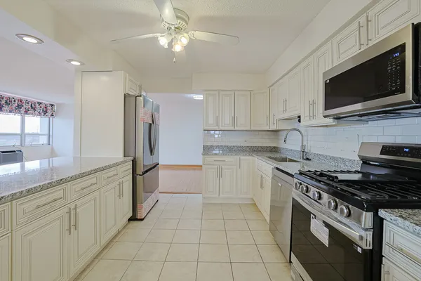 a white kitchen with stainless steel appliances granite countertop a sink and a stove