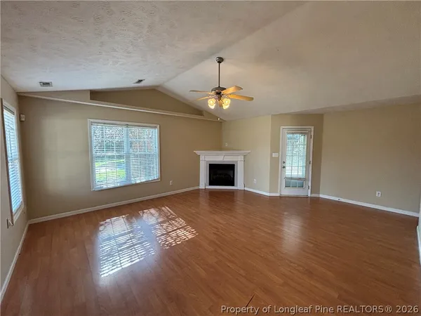 an empty room with wooden floor chandelier and windows