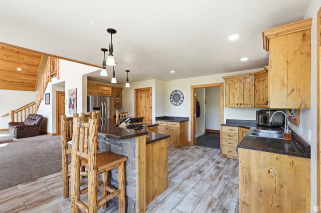 306 Spring Road Preston, ID 83263 - Photo 11 of 55 Kitchen featuring wood-finish flooring, custom wood cabinetry, dark stone countertops, and a stone-clad island with pendant lighting