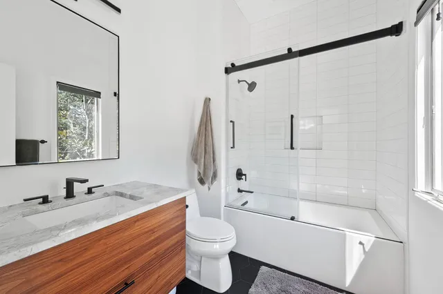 a bathroom with a granite countertop sink toilet tub and shower