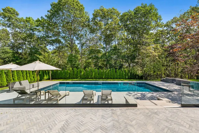 a view of swimming pool with lawn chairs under an umbrella