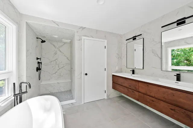 a bathroom with a double vanity sink a mirror and a bathtub