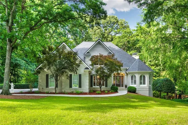 a view of a house with a yard and large trees