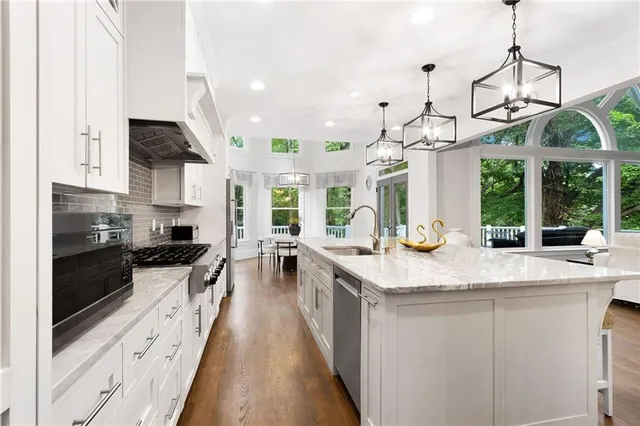 a kitchen with stainless steel appliances granite countertop a sink a stove and a wooden floors