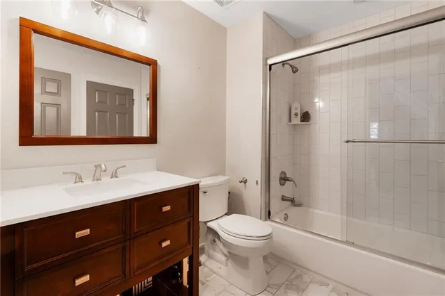 a bathroom with a toilet a sink a mirror a shower a vanity and window