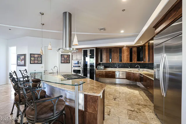 a kitchen with stainless steel appliances kitchen island granite countertop a refrigerator oven a sink and dishwasher