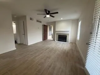 an empty room with wooden floor fireplace and windows