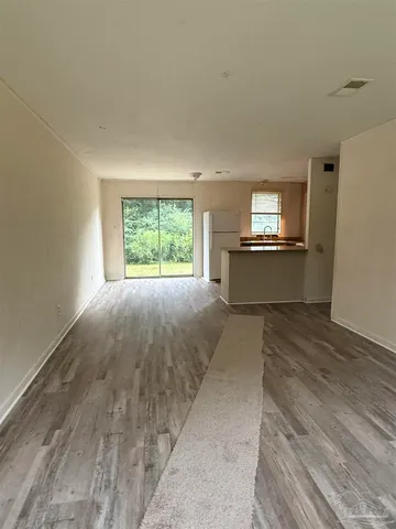 a large white kitchen with kitchen island granite countertop a stove a sink and a dishwasher with wooden floor