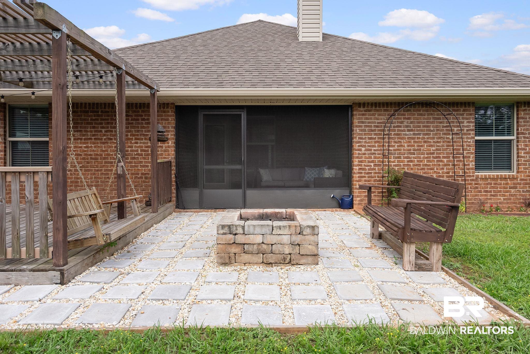 22076 Garland Loop Silverhill, AL 36576 - Photo 20 of 27 Outdoor living area featuring a rectangular paver patio with gravel infill, a stone-built fire pit, and a screened-in porch entrance