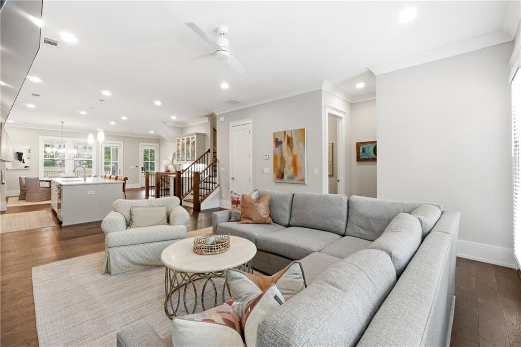 a living room with furniture kitchen view and a wooden floor