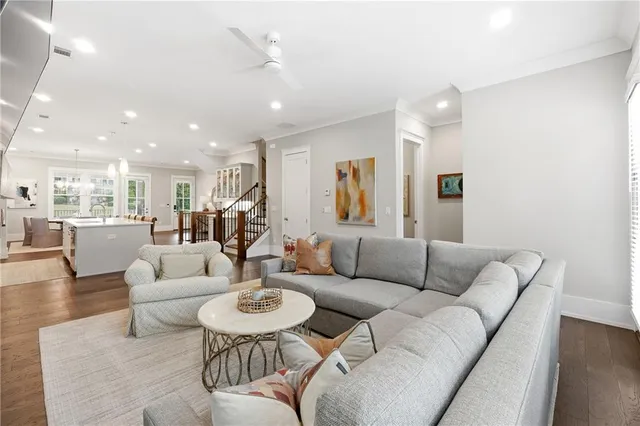 a living room with furniture kitchen view and a wooden floor