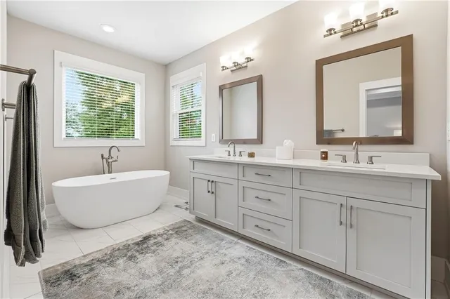 a spacious bathroom with double vanity sink a mirror a bathtub and window