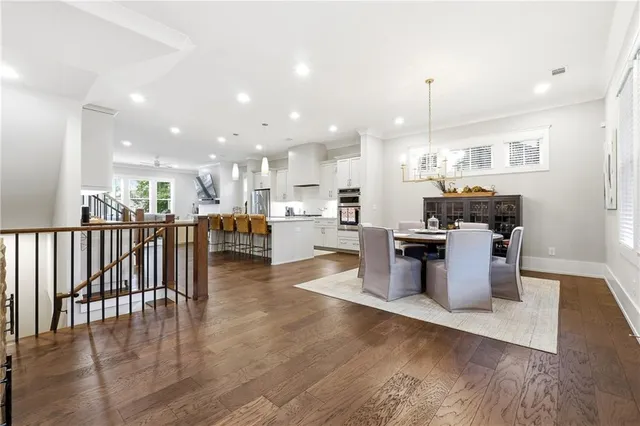 a kitchen with stainless steel appliances kitchen island granite countertop a stove top oven a sink and a dining table with wooden floor