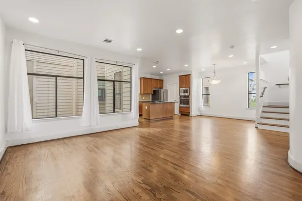 a kitchen with stainless steel appliances granite countertop a stove top oven a sink dishwasher a refrigerator and a dining table with wooden floor