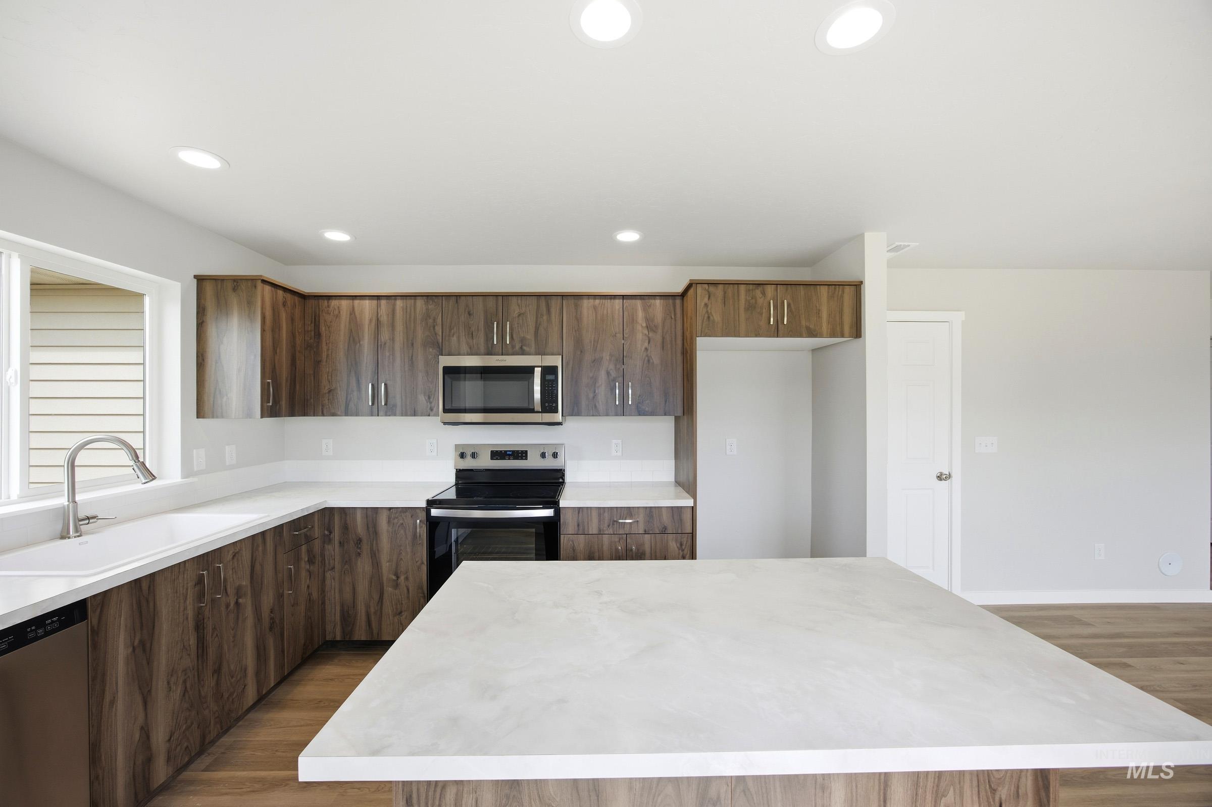 14044 Shiny Spruce Street Caldwell, ID 83607 - Photo 5 of 24 Kitchen showcasing wood-finish cabinetry, light countertops, and an island