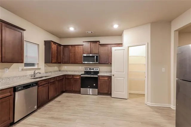 a modern kitchen with stainless steel appliances granite countertop a refrigerator and a sink