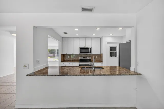 a kitchen with granite countertop white cabinets and stainless steel appliances