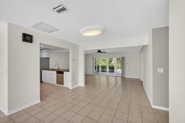a view of an empty room with a window and kitchen view