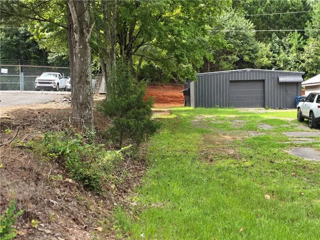 a view of a backyard with large trees and wooden fence