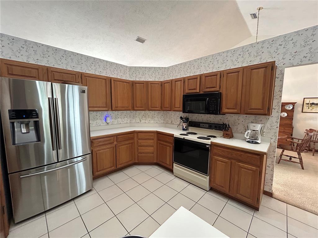 9528 Southeast 70th Terrace Ocala, FL 34472 - Photo 4 of 43 a kitchen with stainless steel appliances granite countertop a refrigerator stove a sink dishwasher and microwave