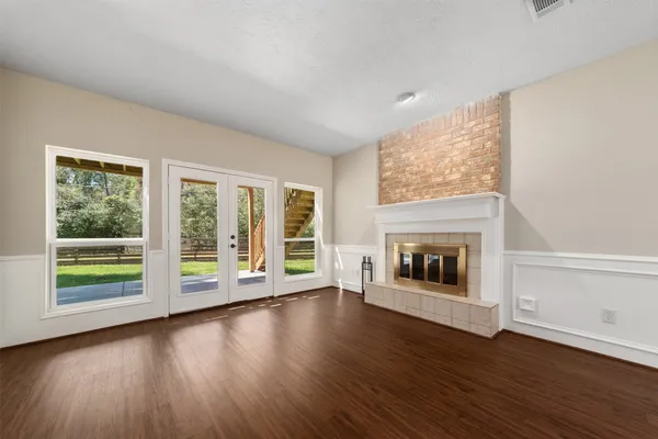 a view of a big room with wooden floor fire place and windows