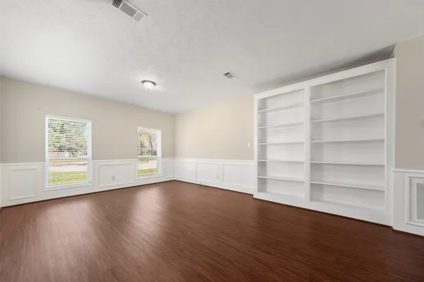 a view of an empty room with a window and wooden floor