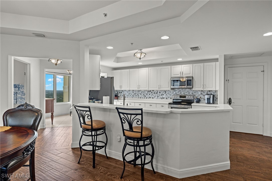 2745 First Street, Unit 1906 Fort Myers, FL 33916 - Photo 8 of 33 a kitchen with stainless steel appliances a dining table chairs and wooden floor