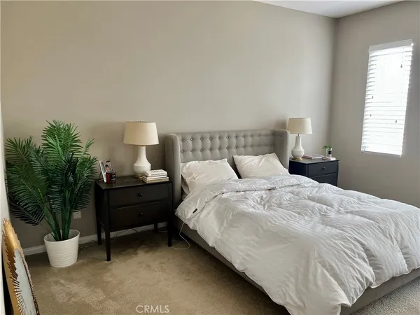 a large bed sitting in a bedroom next to a window and potted plant
