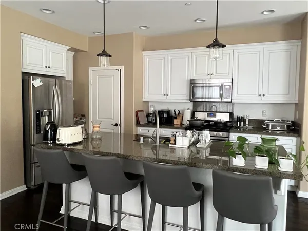 a kitchen with stainless steel appliances granite countertop a table chairs refrigerator and cabinets