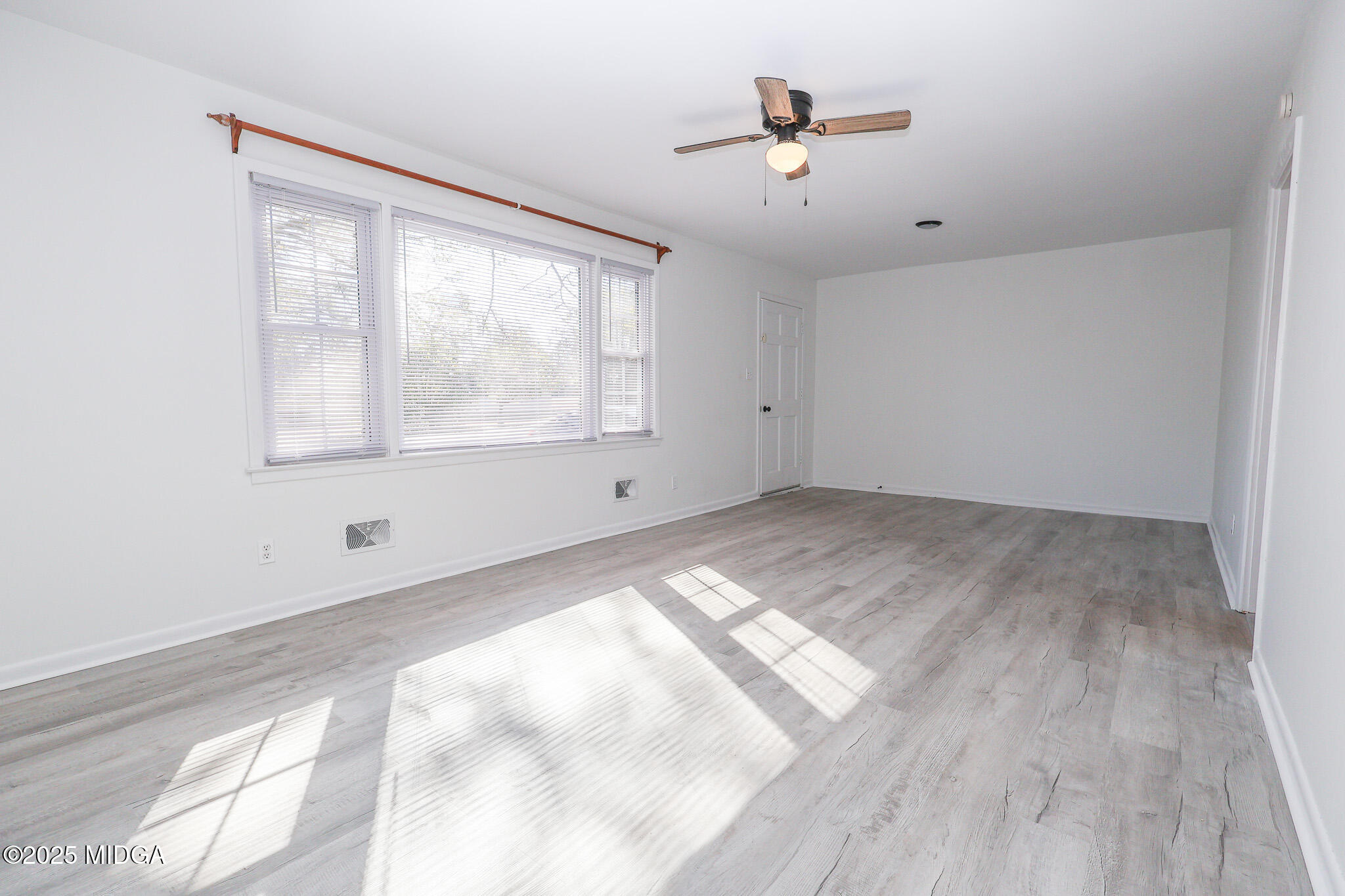 105 Larryton Drive Cochran, GA 31014 - Photo 7 of 34 an empty room with wooden floor and windows