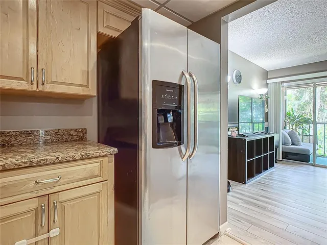 a living room with couches a coffee table a flat screen tv and a large window with kitchen view
