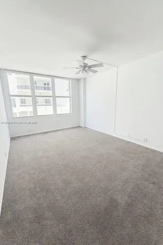 an empty room with windows and chandelier fan