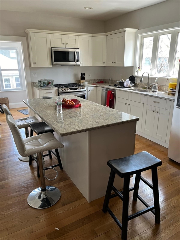 72 Bristow Street Saugus, MA 01906 - Photo 3 of 7 a kitchen with a stove a sink dishwasher a dining table and chairs with wooden floor