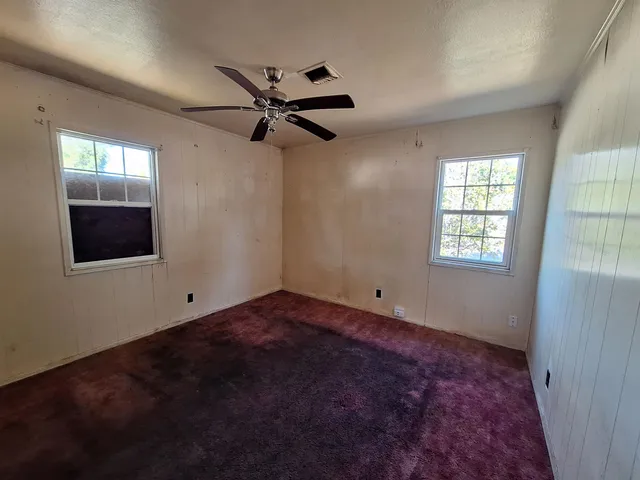 a view of empty room with wooden floor and ceiling fan