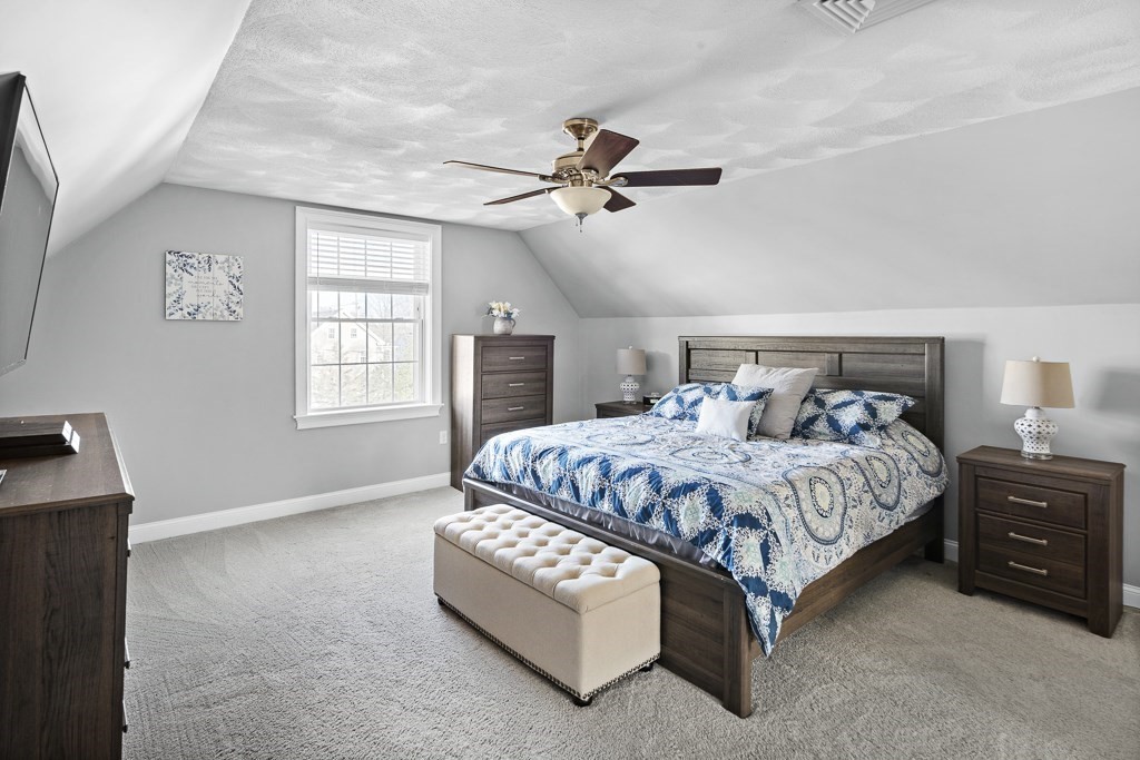 2 Willow Avenue Danvers, MA 01923 - Photo 31 of 42 a spacious bedroom with a bed a chandelier and a window