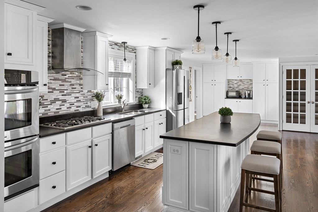 2 Willow Avenue Danvers, MA 01923 - Photo 5 of 42 a kitchen with stainless steel appliances kitchen island granite countertop a sink a microwave a refrigerator and white cabinets with wooden floor