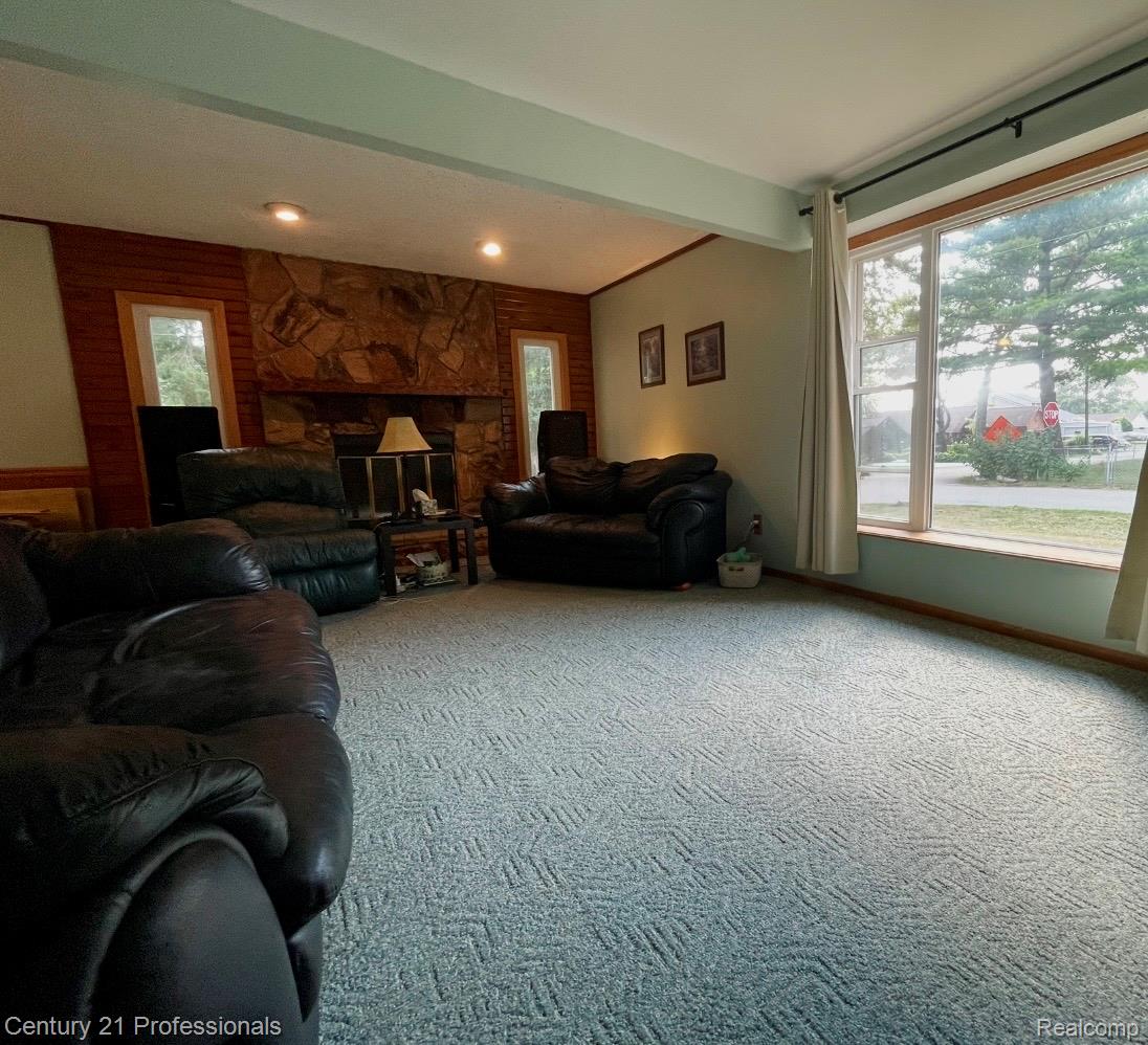2903 Lake Angelus Road Waterford, MI 48329 - Photo 2 of 17 Spacious living area featuring a stone-clad fireplace surround, recessed lighting, wood paneling, a large picture window, and patterned carpeting