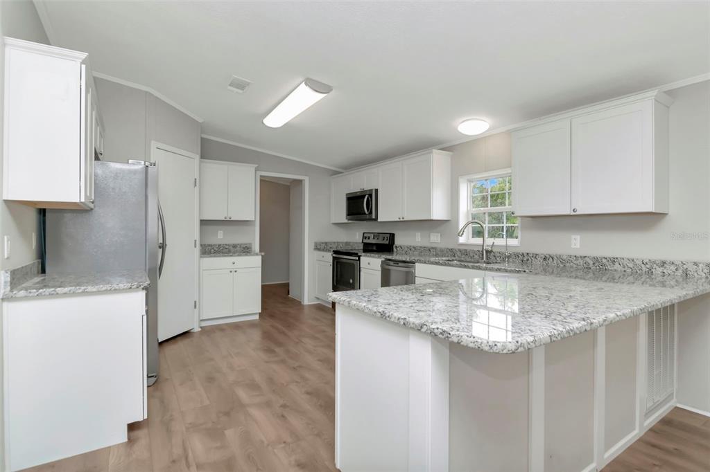 5213 R M D Avenue Plant City, FL 33566 - Photo 16 of 32 a kitchen with stainless steel appliances granite countertop a sink stove and refrigerator