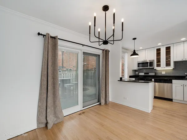 a kitchen with stainless steel appliances a dining table chairs and couches with wooden floor