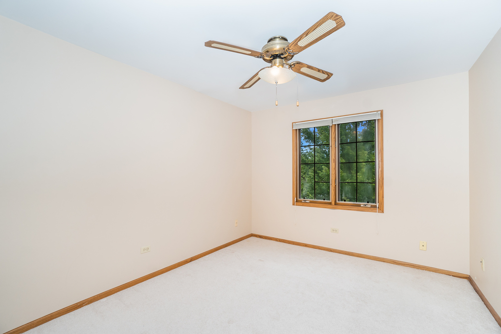 812 Meadow Ridge Lane, Unit 107 New Lenox, IL 60451 - Photo 11 of 15 an empty room with a window and ceiling fan