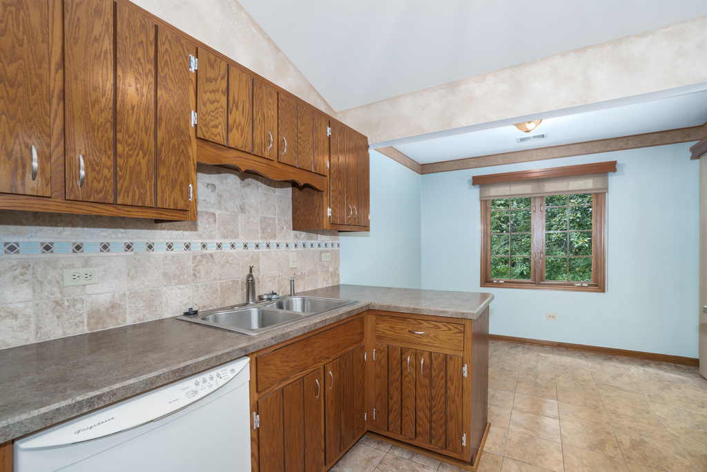 812 Meadow Ridge Lane, Unit 107 New Lenox, IL 60451 - Photo 4 of 15 a kitchen with stainless steel appliances granite countertop wooden cabinets a sink and dishwasher