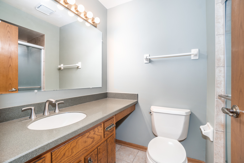 812 Meadow Ridge Lane, Unit 107 New Lenox, IL 60451 - Photo 8 of 15 a bathroom with a granite countertop toilet sink and a mirror