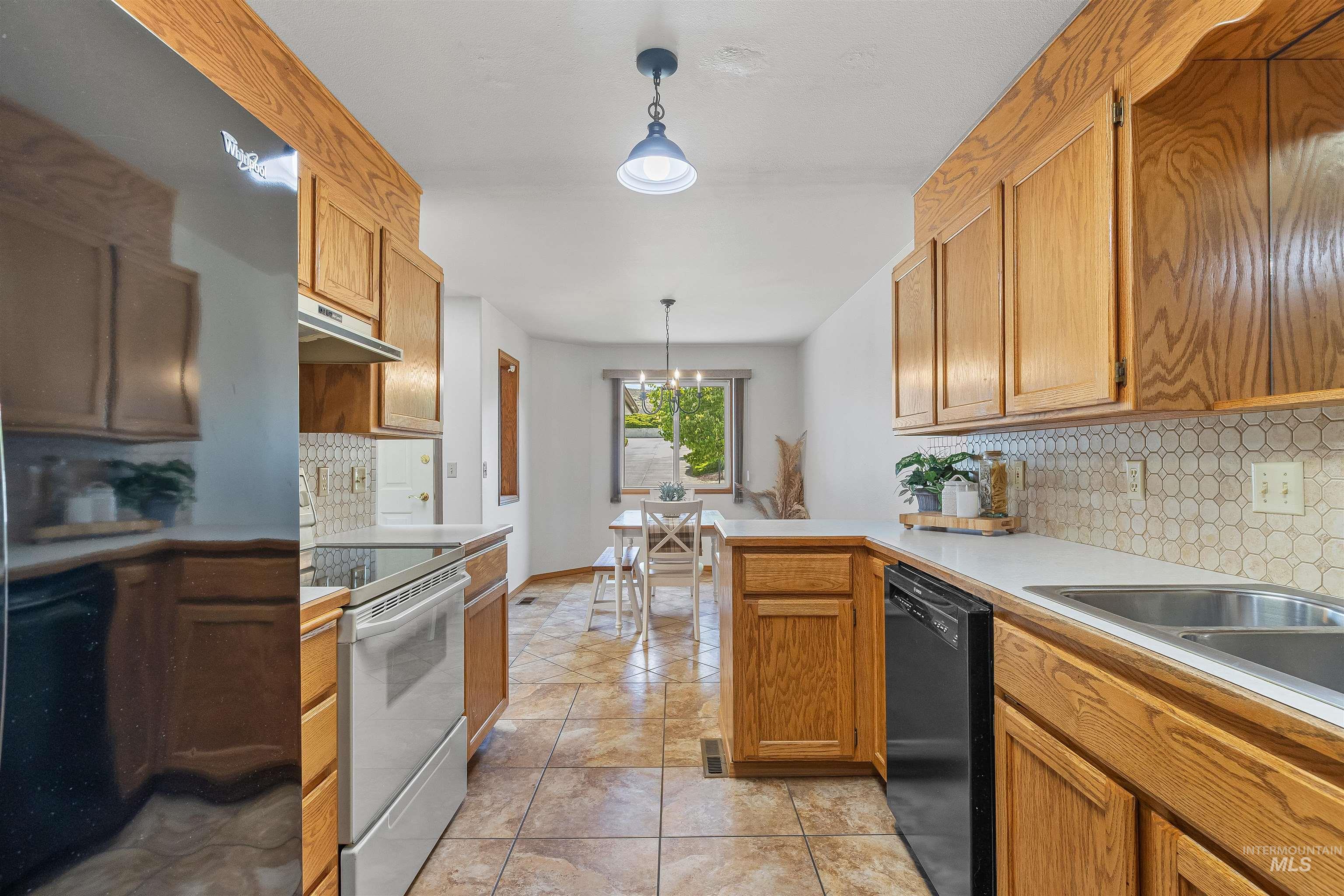 1409 29th Street Lewiston, ID 83501 - Photo 9 of 30 Kitchen with white range with electric cooktop, backsplash, hanging light fixtures, light countertops, and black dishwasher
