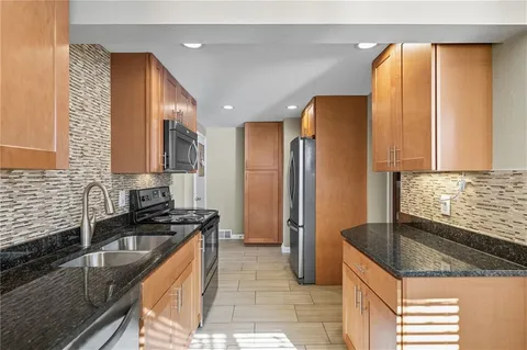 a kitchen with stainless steel appliances granite countertop a sink a stove and a refrigerator