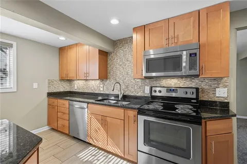 a kitchen with granite countertop wooden cabinets stainless steel appliances and a sink