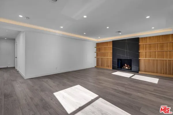 a view of an empty room with wooden floor fireplace and a window