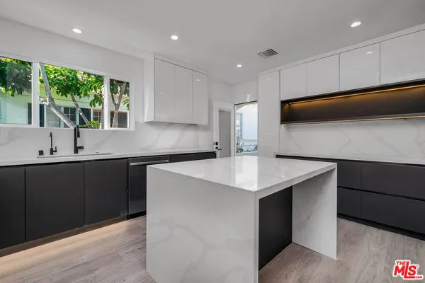 a kitchen with kitchen island a sink appliances and cabinets