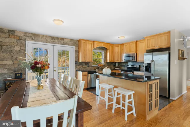 a kitchen with stainless steel appliances granite countertop a stove a refrigerator a kitchen island and chairs in it